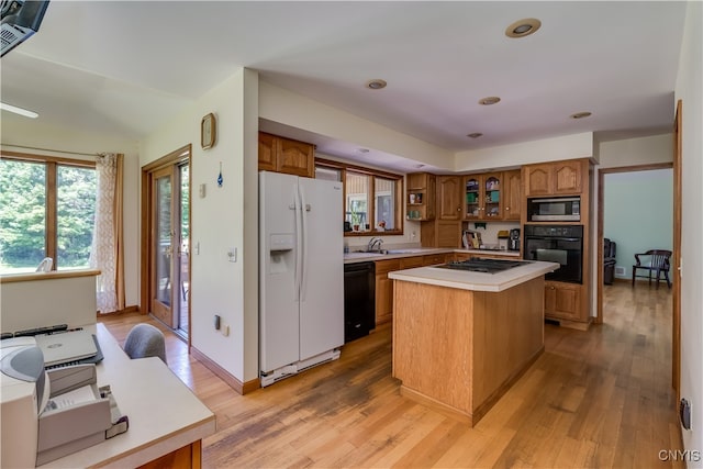 kitchen featuring sink, a kitchen island, black appliances, and light hardwood / wood-style floors