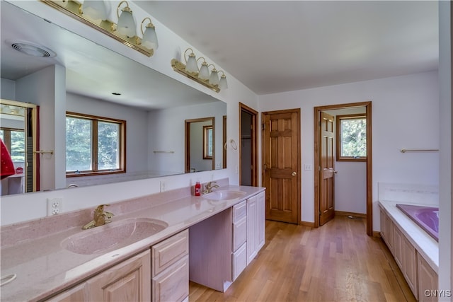 bathroom featuring hardwood / wood-style floors, double vanity, plenty of natural light, and a bath