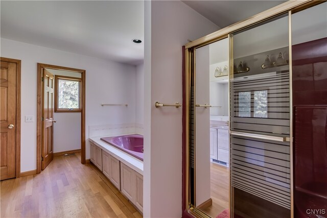 bathroom featuring plus walk in shower and hardwood / wood-style flooring