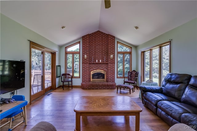 living room with brick wall, a fireplace, hardwood / wood-style floors, and lofted ceiling