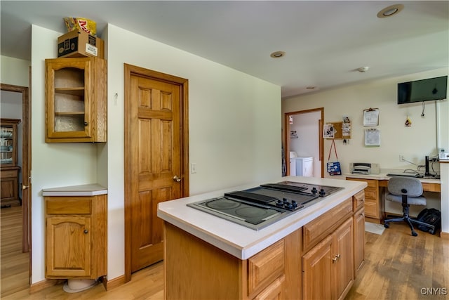 kitchen featuring independent washer and dryer, light hardwood / wood-style flooring, gas cooktop, and a center island