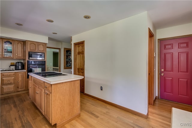 kitchen featuring stainless steel microwave, light hardwood / wood-style flooring, oven, gas stovetop, and a center island