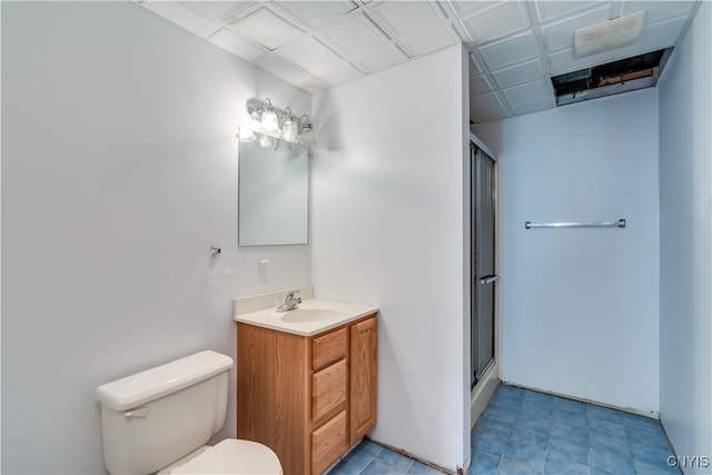 bathroom featuring a shower with shower door, vanity, toilet, and tile patterned flooring