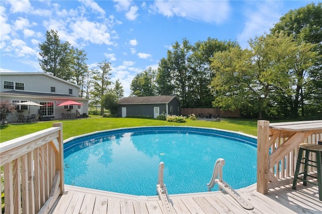 view of swimming pool featuring a wooden deck, a yard, and an outdoor structure