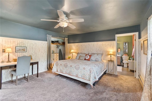 bedroom featuring a baseboard radiator, wood walls, and carpet flooring