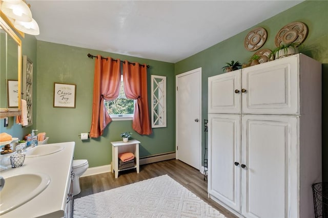 bathroom with vanity, toilet, hardwood / wood-style floors, and a baseboard heating unit