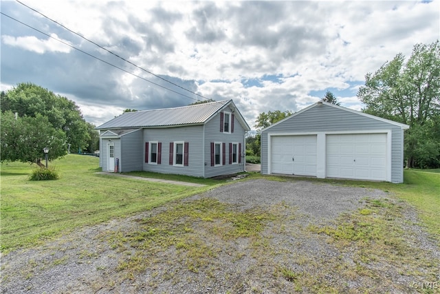 view of front of house featuring a garage, a front lawn, and an outbuilding