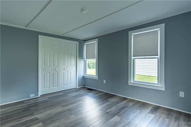 unfurnished bedroom with hardwood / wood-style floors, a closet, and multiple windows