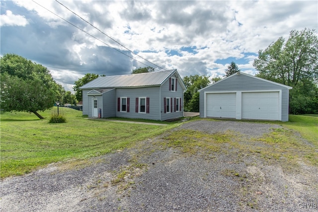 exterior space with a garage, a front lawn, and an outbuilding