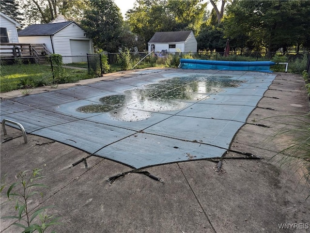 view of swimming pool with fence, an outdoor structure, and a storage shed