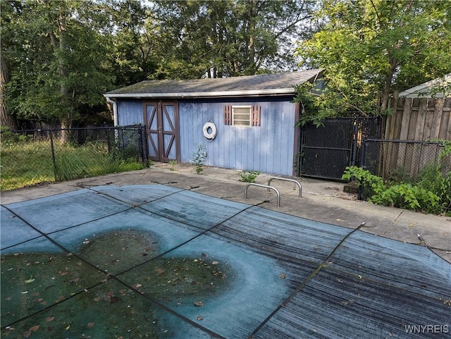 view of swimming pool with an outbuilding, a fenced backyard, and a shed