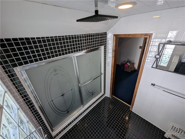 full bath featuring tile walls, a tile shower, healthy amount of natural light, and tile patterned floors