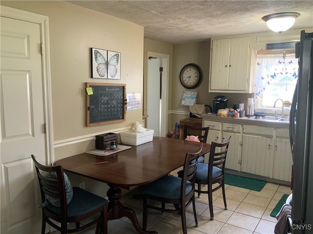 tiled dining room featuring sink and a textured ceiling