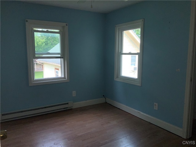 spare room with hardwood / wood-style floors and a baseboard heating unit