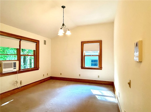 carpeted spare room with cooling unit, lofted ceiling, plenty of natural light, and a chandelier