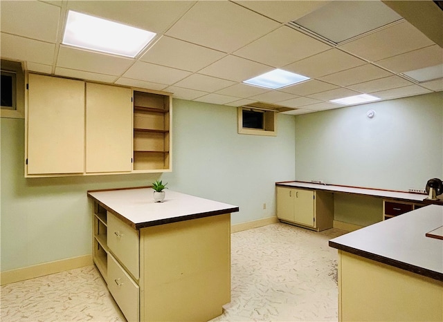 kitchen featuring kitchen peninsula, a drop ceiling, cream cabinets, and light carpet