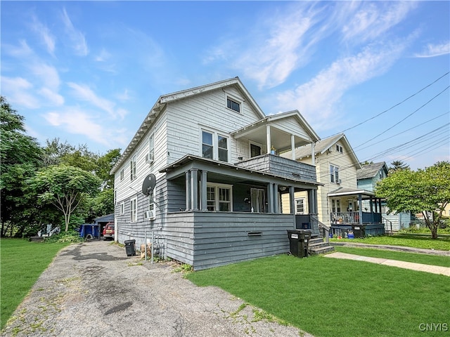 view of front of home with a balcony and a front yard