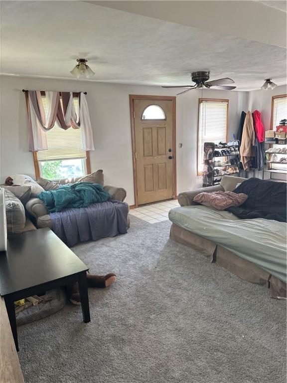 living room with ceiling fan, a textured ceiling, and light colored carpet