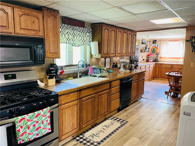 kitchen with sink, light hardwood / wood-style flooring, a drop ceiling, and black appliances