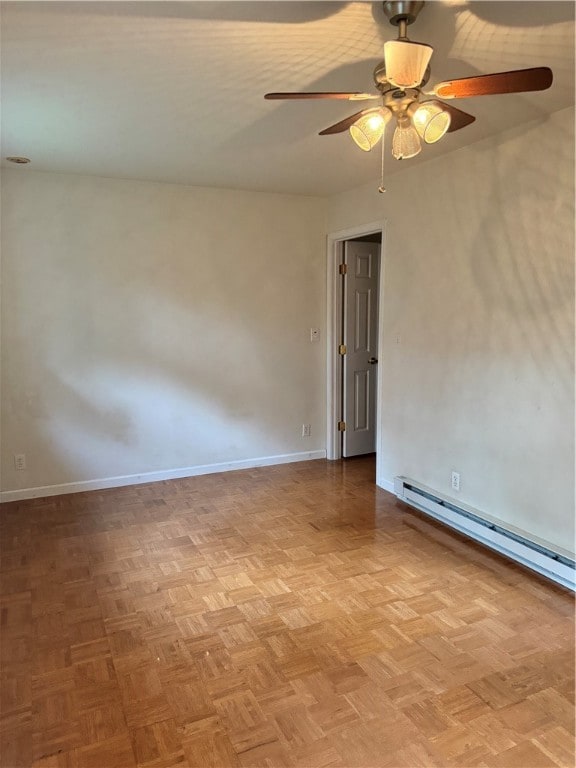 empty room featuring ceiling fan, parquet flooring, and a baseboard heating unit