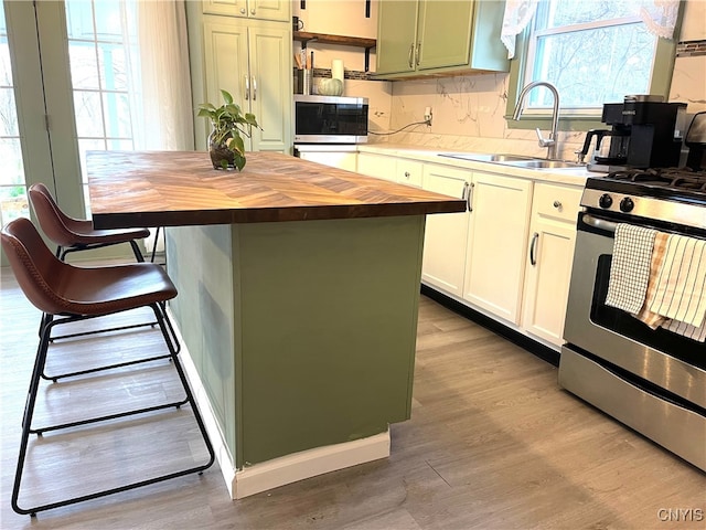 kitchen featuring a kitchen bar, light wood-type flooring, stainless steel appliances, sink, and a kitchen island