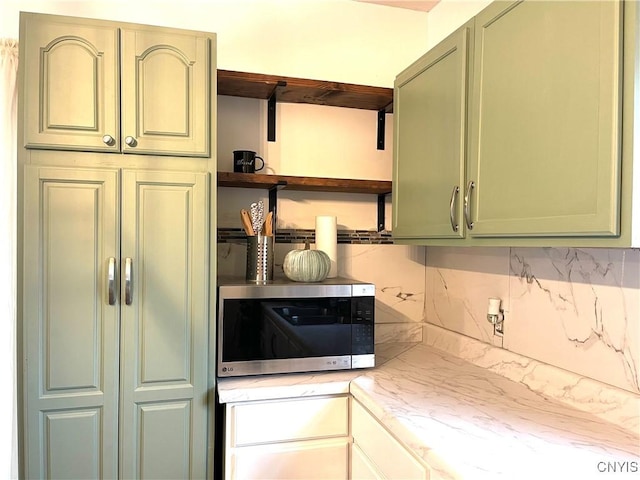 132 E Remington St, Rutland, NY 13612 - kitchen with stainless steel microwave, open shelves, backsplash, green cabinetry, and light stone countertops