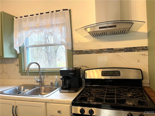 kitchen featuring island exhaust hood, tasteful backsplash, gas stove, sink, and white cabinets