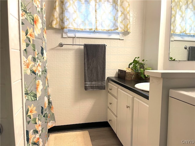 bathroom with hardwood / wood-style floors, vanity, and tile walls