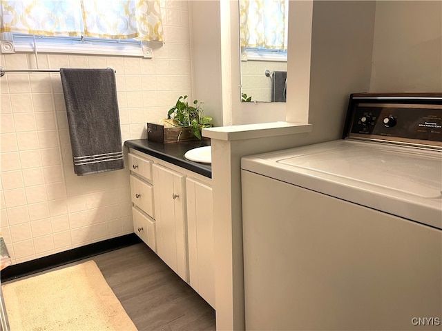 washroom featuring washer / dryer, dark wood-type flooring, and tile walls