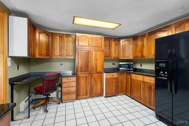 kitchen featuring dark stone counters, black refrigerator with ice dispenser, built in desk, and light tile patterned floors