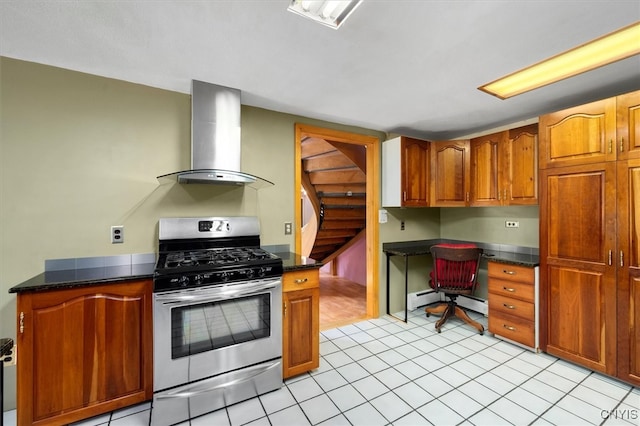 kitchen with gas range, wall chimney exhaust hood, built in desk, light tile patterned floors, and dark stone countertops