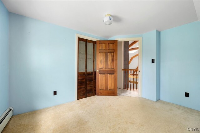 unfurnished bedroom featuring light hardwood / wood-style floors, a closet, and baseboard heating