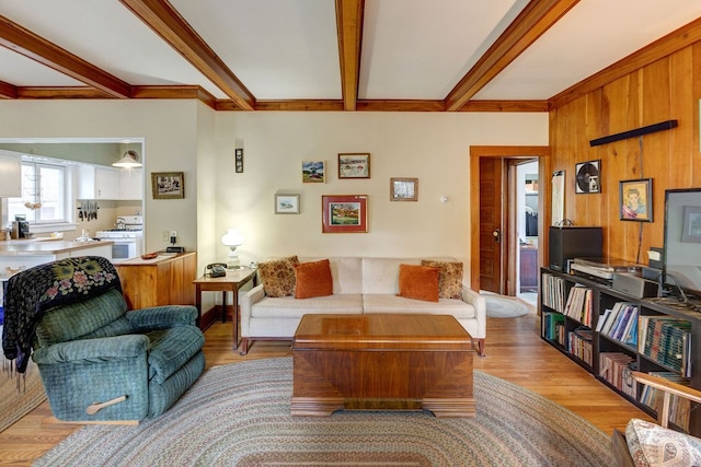 living room featuring beamed ceiling and light wood-type flooring