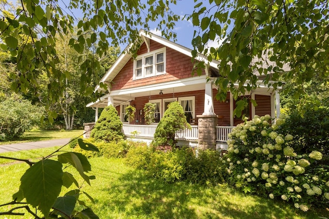 rear view of house featuring covered porch and a yard