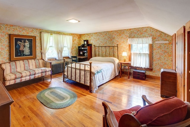 bedroom featuring hardwood / wood-style flooring, lofted ceiling, and radiator