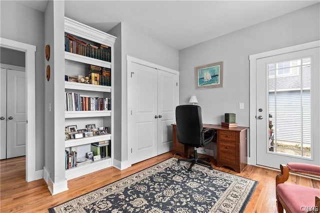 office featuring light hardwood / wood-style floors, built in shelves, and a healthy amount of sunlight