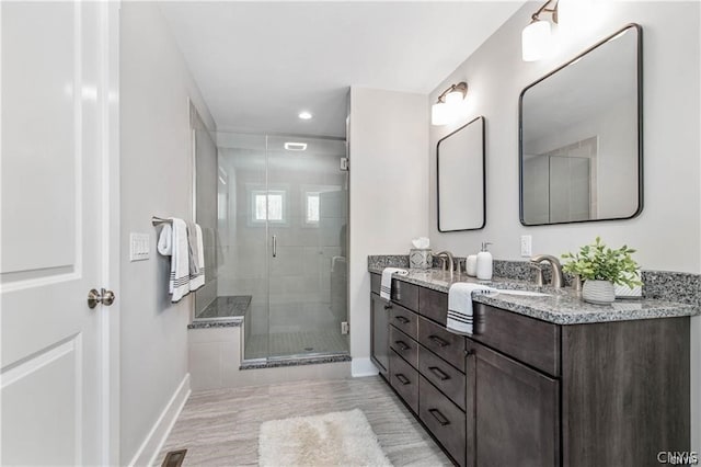 bathroom featuring dual bowl vanity and a shower with door