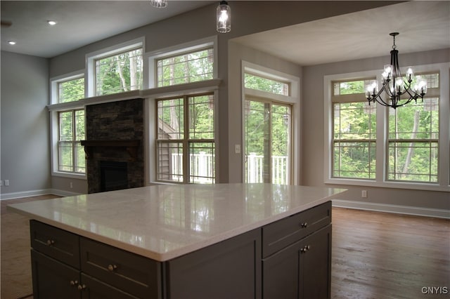 kitchen with a stone fireplace, wood-type flooring, and a healthy amount of sunlight