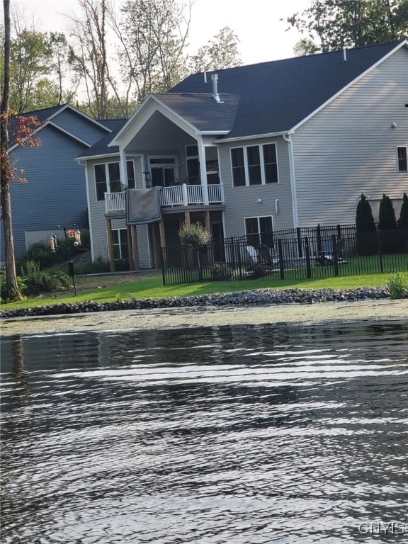 view of front of home featuring a balcony, a front lawn, and a water view