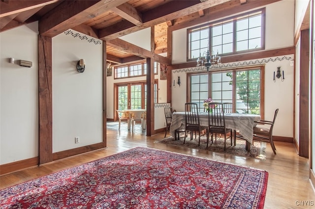 dining room with beamed ceiling, a notable chandelier, and light hardwood / wood-style flooring