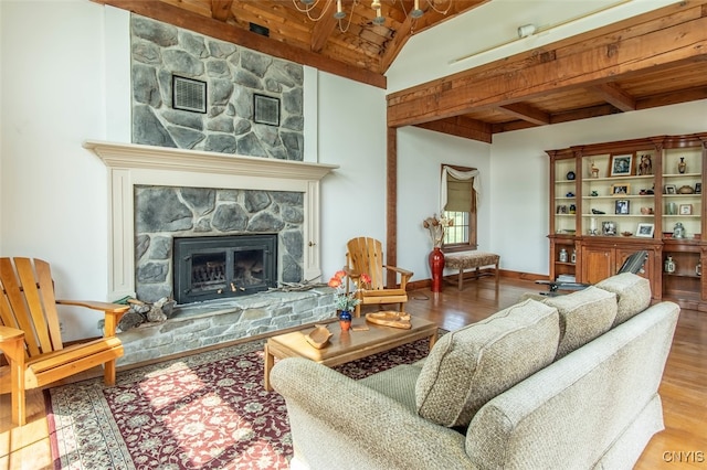 living room featuring beam ceiling, hardwood / wood-style floors, wood ceiling, and a stone fireplace