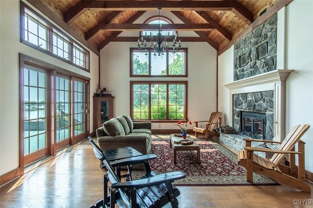 27454 County Route 57, Lyme, NY 13693 - living room with a stone fireplace, wooden ceiling with exposed beams, a chandelier, hardwood / wood-style flooring, and high vaulted ceiling