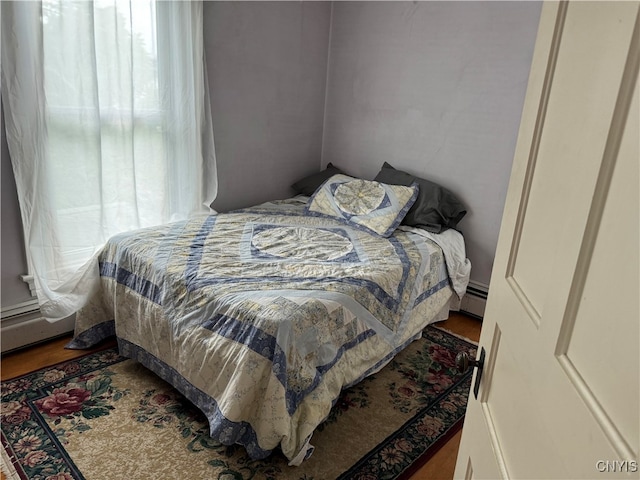 bedroom featuring hardwood / wood-style floors and a baseboard heating unit