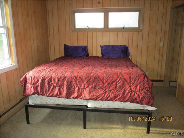 bedroom with wooden walls, carpet, and multiple windows