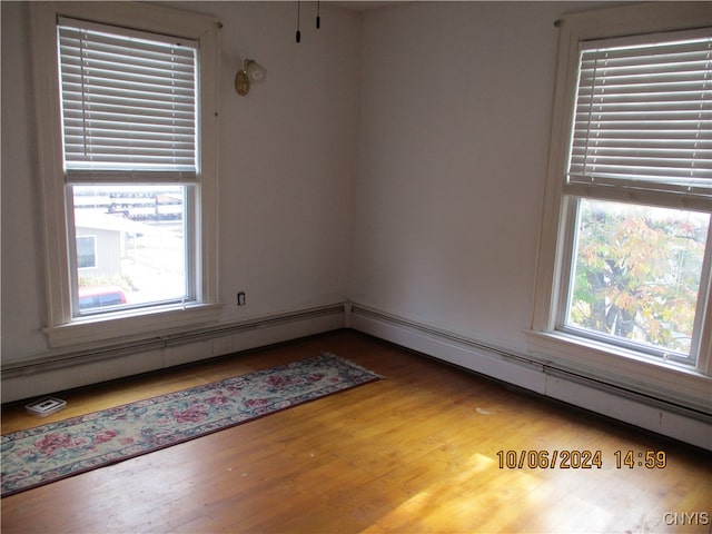 unfurnished room featuring wood-type flooring and a baseboard heating unit