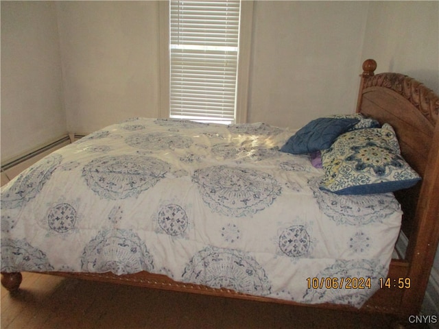 bedroom featuring baseboard heating and hardwood / wood-style floors