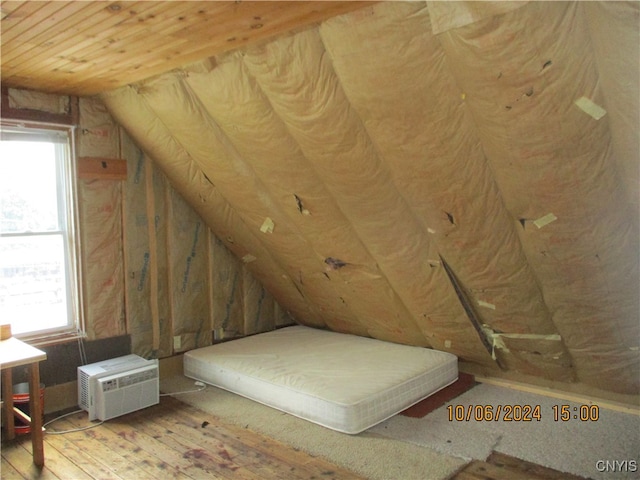 bedroom featuring a wall unit AC, light hardwood / wood-style flooring, multiple windows, and lofted ceiling