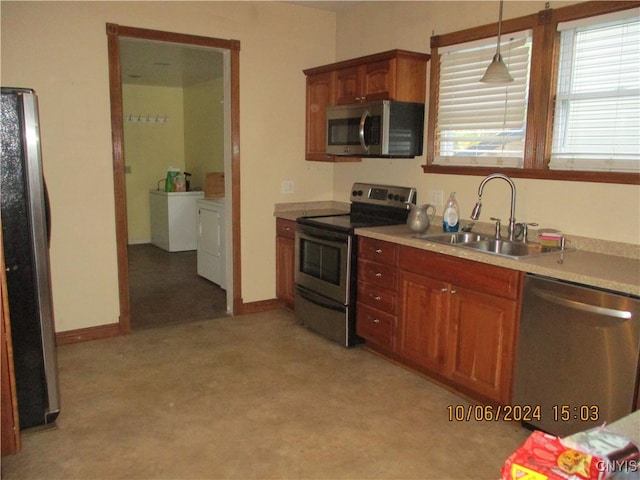 kitchen featuring sink, hanging light fixtures, light carpet, stainless steel appliances, and washer and clothes dryer