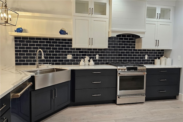 kitchen featuring stainless steel range oven, white cabinetry, sink, and light hardwood / wood-style flooring