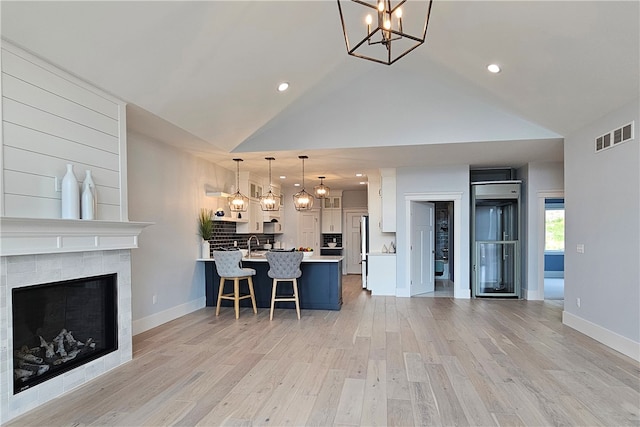 interior space with white cabinets, hanging light fixtures, light hardwood / wood-style flooring, a chandelier, and a breakfast bar area